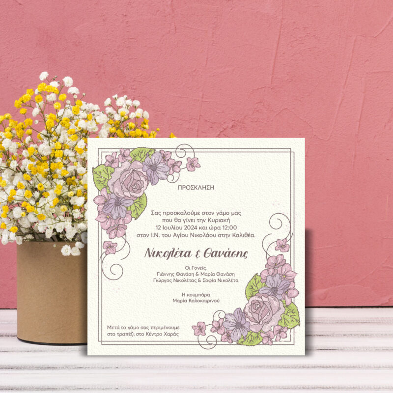 Πρόσκληση γάμου 155x155 χιλ. με ρομαντικό floral σχέδιο σε ροζ και λιλά αποχρώσεις, τοποθετημένο μπροστά σε ροζ τοίχο, δίπλα σε ένα βάζο με κιτρινωπά λουλούδια.